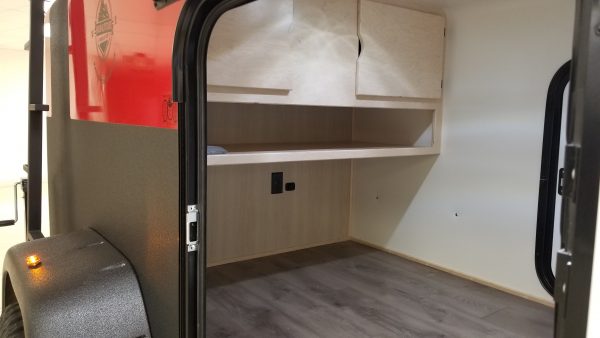 View of main sleeping area and storage cabinets through the open door of an Adventure camping trailer at Earthship Overland at their showroom in Englewood, CO
